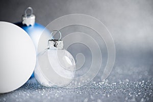 Blue, silver and white xmas ornaments on glitter holiday background. Merry christmas card.