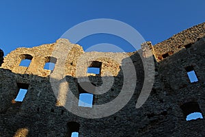 Blue skies and various windows in remains of eastern wall of early gothic inner courtyard of castle Topolcany, Slovakia