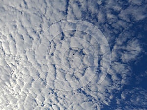 Blue sky background with clouds. Cirro-cumulus clouds on a blue sky on a sunny day. Cirrus sky. the plane is crossing the clouds photo