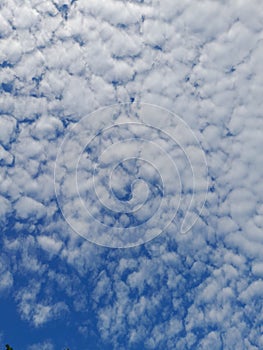 Blue sky background with clouds. Cirro-cumulus clouds on a blue sky on a sunny day. Cirrus sky. Spindrift clouds. photo