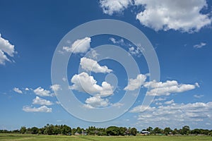Blue sky background with green fields and white clouds