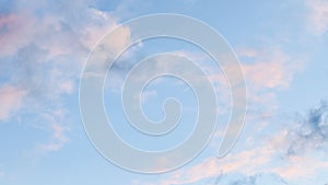 Blue sky background with pale pink clouds at sunset