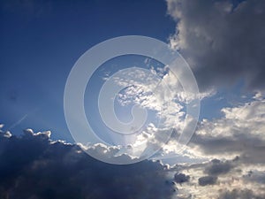 Blue sky background with the sun and rays behind the clouds. Sky heaven.