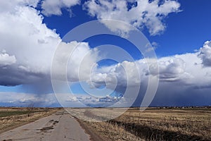 Blue sky background with thunderclouds and country road. Blue, white pastel paradise, soft focus lenses, glare of sunlight.