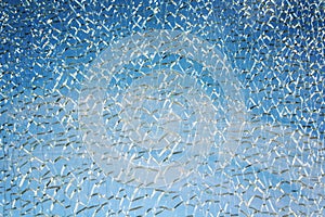 Blue sky behind broken glass surface. Aged photo.