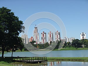Blue sky, buildings in the background, trees and plants, lake in Barigui park in the tourist city of Curitiba photo
