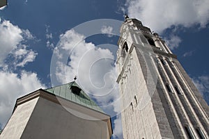 Blue sky with clouds behind white belfry church of Cortina d`Ampezzo, Veneto, Italy.