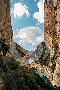 Blue sky with clouds between narrow rocky cliffs. River in Congost de Mont Rebei gorge in Catalonia, Spain. Natural