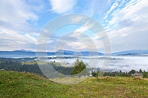 Blue sky with clouds over green meadows and mountains. Ukraine, Carpathians