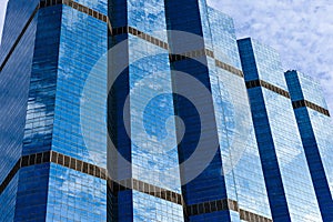 Blue sky and clouds reflected on the glass of office business buildings in the city center on a bright sunny day