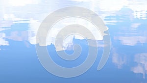 Blue sky and clouds reflected on a rippling water surface