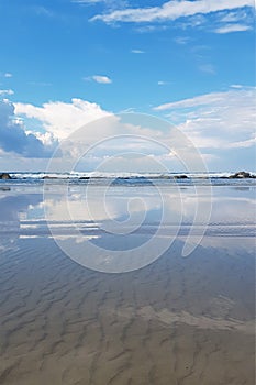 Blue sky and clouds are reflected in the water. Sea shore. The concept of calm and conciliation.