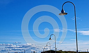 Blue sky with clouds and street lights in Ventspils, Latvia