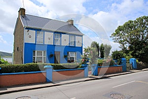 Blue sky with clouds and a striking blue house in the village Dingle in county Kerry in Ireland in the summer.
