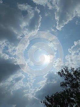 Blue sky with clouds and sun playing hide and seek.