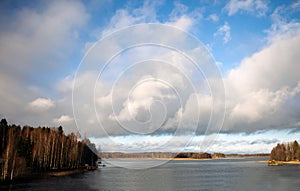 Blue sky with clouds and sun reflection in water with place for your text. amazing clouds, lake in the Finland and the