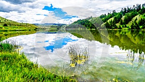 Blue Sky, Clouds and surrounding Mountains reflecting on the smooth water surface of Trapp Lake