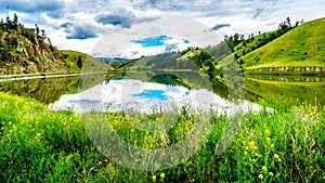 Blue Sky, Clouds and surrounding Mountains reflecting on the smooth water surface of Trapp Lake