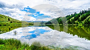 Blue Sky, Clouds and surrounding Mountains reflecting on the smooth water surface of Trapp Lake