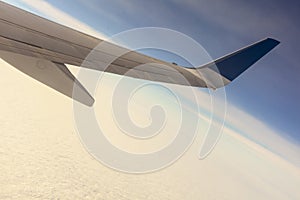 Blue sky with clouds under the wing of an airplane.