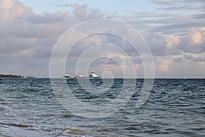 Blue sky with clouds and sea with boats in the sunset background