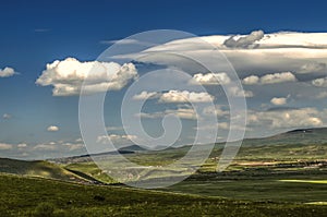 Blue sky from with cold wind blowing from the mountains of the Geghama range moves turbulent cloud with Cumulus clouds covering th