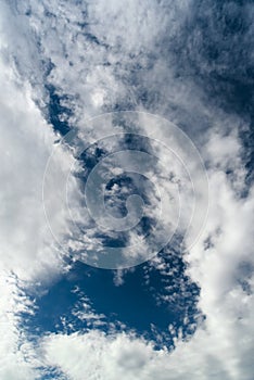 Blue sky with cumulus white clouds. Beautiful cloudscape. Abstract background. Vertical orientation