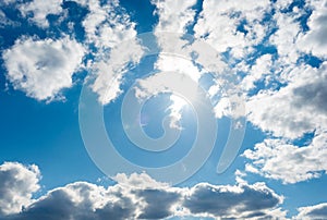 Blue sky with dense white clouds and sun beams. The sun rays through the clouds