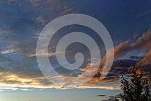 Blue sky with gold clouds - dramatic sunset, beautiful natural background. Setting sun illuminates the clouds.