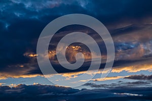 Blue sky with gold clouds - dramatic sunset, beautiful natural background. Setting sun illuminates the clouds