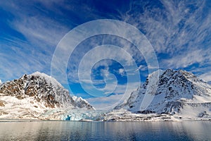 Blue sky with ice floe. Beautiful landscape. Cold sea water. Land of ice. Travelling in Arctic Norway. White snowy mountain, blue