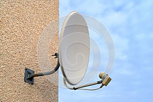 Blue sky on its background white old satellite dish on a multi-storey building