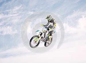 Blue sky, jump and man on motorbike in air for practice, training and extreme sports energy. Professional dirt biking