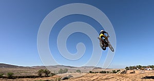 Blue Sky, male person and motorcycle jump with low angle for performance, extreme sports stunt and adrenaline