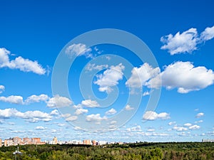 Blue sky with many white clouds over wood and city