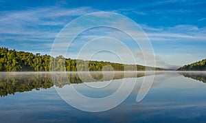 Blue sky misty summer morning in middle of Corry lake.