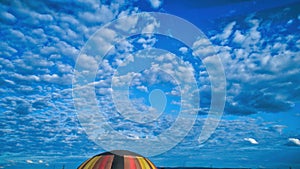 Blue sky and multiple clouds and a hot air balloon