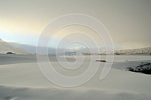 Blue sky over fjord and tromsoe city island and bridge with snow heavy clouds