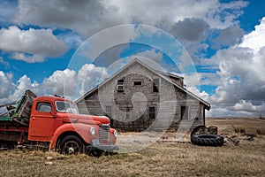 Blue sky over an old, abandoned home and truck on the prairies