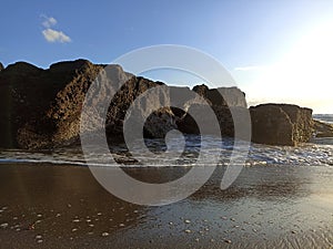 Blue sky over the sea rock with black sands. Beach background. Canggu Beach, Bali, Indonesia