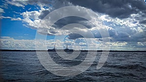 Blue sky over wavy lake landscape, nature background with heavy clouds above and visible Visaginas nuclear power plant