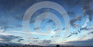 Blue sky panorama with clouds over tops of buildings