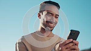 Blue sky, phone and young man typing a text message on social media, mobile app or website. Technology, online and happy