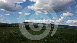 Blue sky, puffy clouds and green terrain