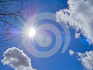 Blue sky with puffy white clouds and rays of light from sun.