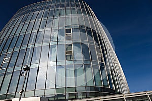 The blue sky is reflected in the windows of a modern office building. Architecture and exterior of contemporary houses