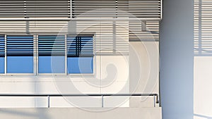 blue sky reflection on glass windows surface with stainless steel awning and railing of balcony on white office building