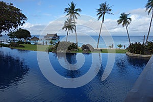 Blue sky, sea and swimming pool with towering coconut trees