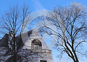 Blue sky With Some Mottled White Clouds Is backdrop for Bare Trees and Beautiful Building Top