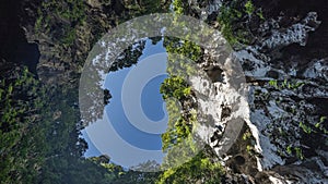 The blue sky surrounded by cliffs is visible from the cave.